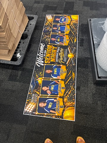 A printed Senior Night banner photographed with its six player portraits