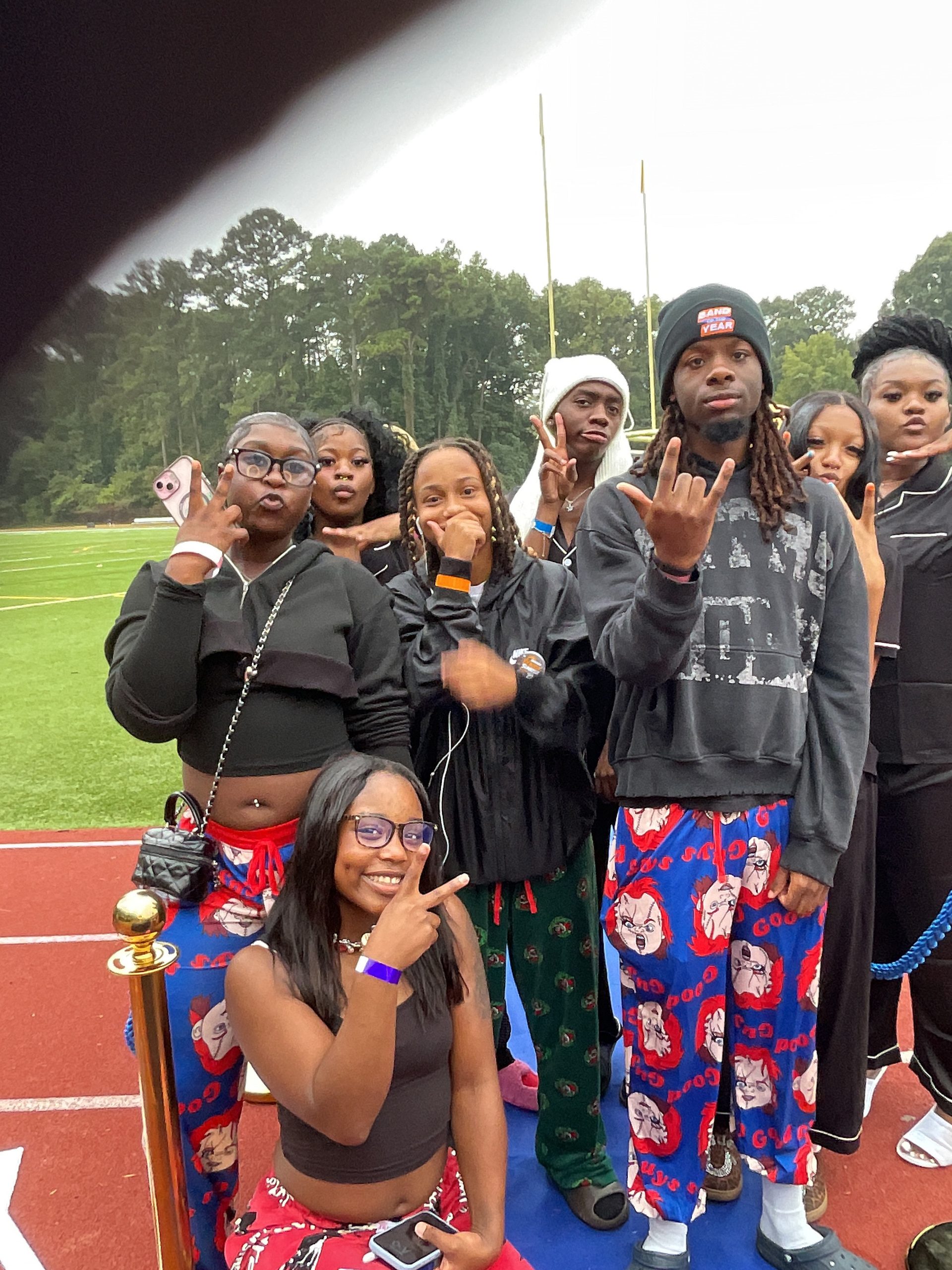 A group of eight seniors posing together on the blue mat laid over the running track