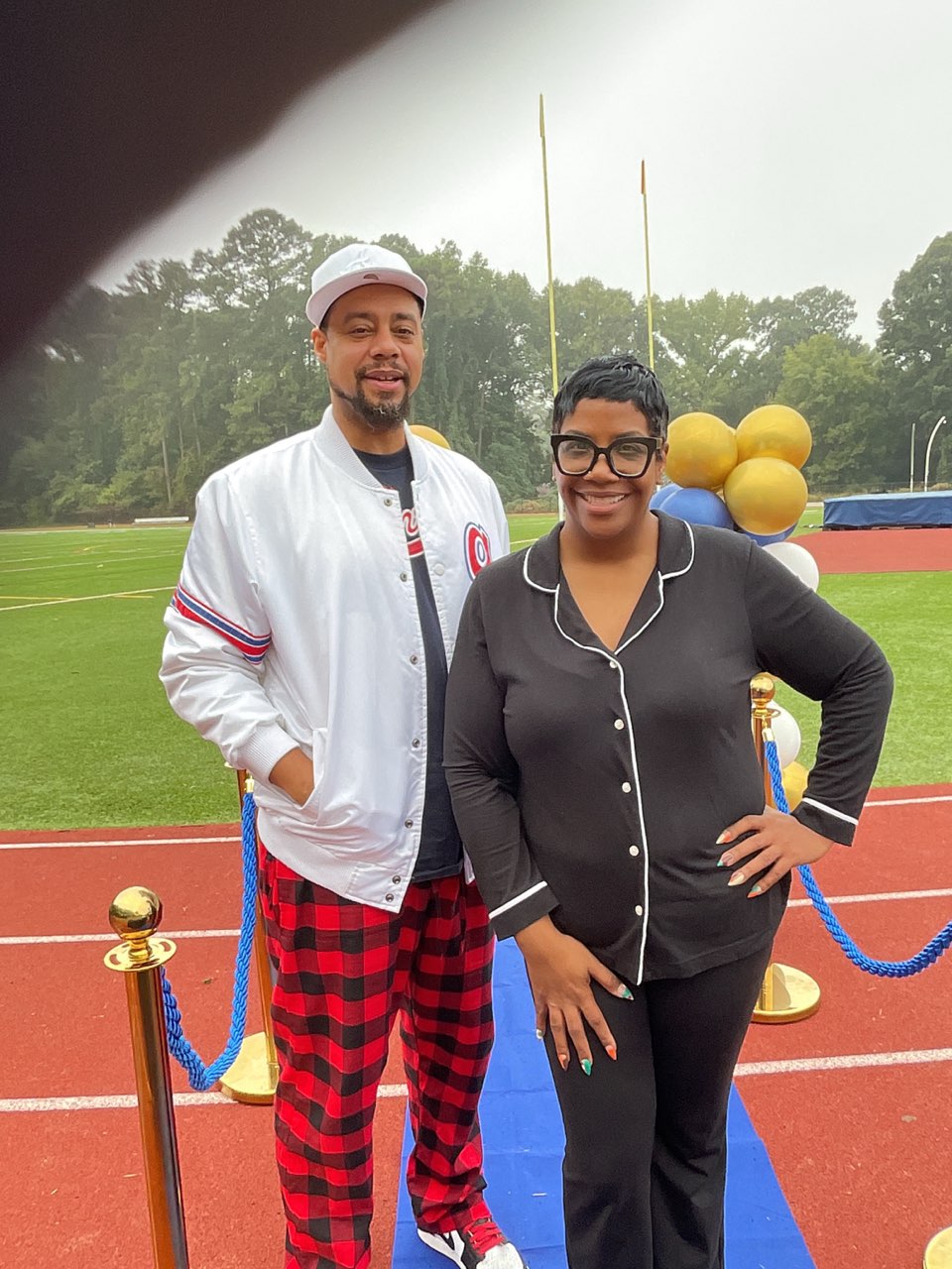 A man in a white and red jacket and plaid pants next to a woman in black on the blue mat